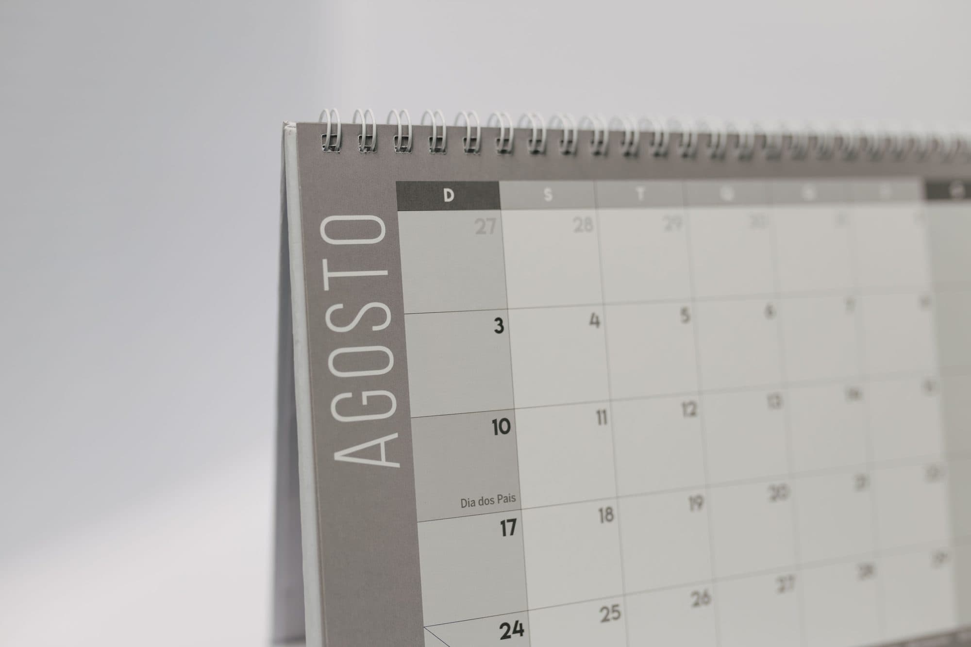 Calendário de mesa aberto na página de agosto, com os dias do mês em quadrinhos, para lembrar o prazo do licenciamento anual