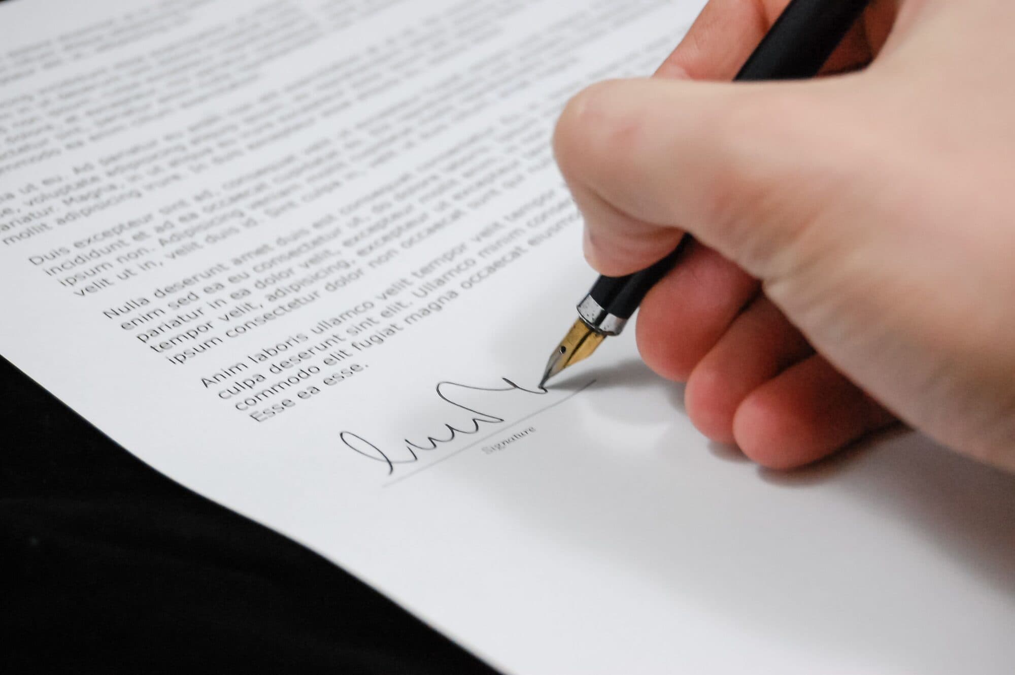 Mão assinando um documento com uma caneta tinteiro
